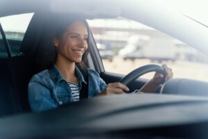 Retrato de mujer latina conduciendo un auto feliz de saber los tipos de licencia de conducir arizona